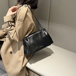 Détails de la texture du cuir noir brillant et de la bandoulière chaîne d'un sac chic