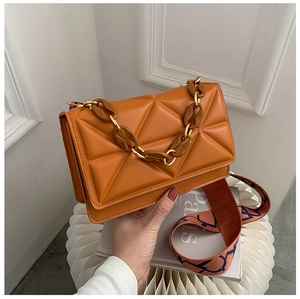 Close-up of orange quilted bag with thick chain handle and woven shoulder strap