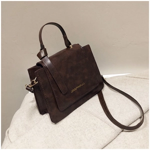 Détail du sac vintage en simili cuir marron avec logo doré et rabat enveloppe