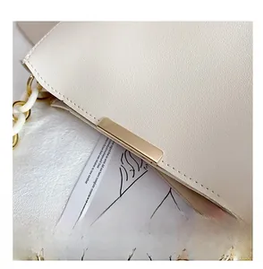 Detail of cream lychee leather bucket bag with gold metal buckle and acrylic chain