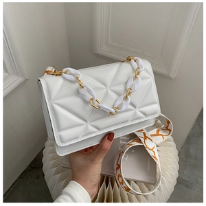 Detail of white quilted geometric shoulder bag with resin chain and orange strap