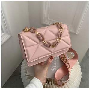 Close-up of pink quilted crossbody bag with chunky resin chain and wide patterned strap
