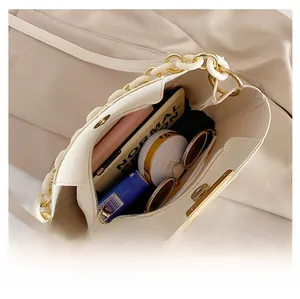 Interior view of cream chain bucket bag showing storage for phone, makeup, and glasses
