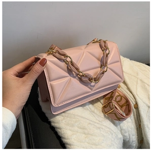 Detail of pink quilted crossbody bag with golden chain handle and canvas strap