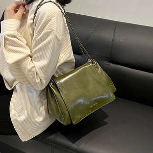 Détail d'un sac en similicuir vert foncé brillant avec chaîne sur mannequin