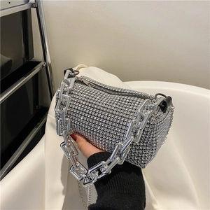 Sac baguette scintillant en strass argentés avec poignée chaîne épaisse porté par un mannequin