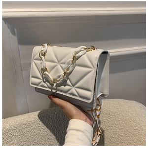 Detail of white quilted handbag with acrylic chain and geometric print shoulder strap