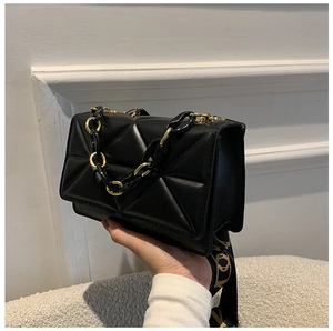 Detail of black quilted leather shoulder bag with gold chain and letter print strap
