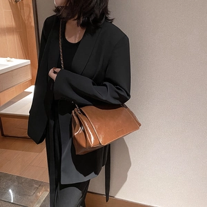 Sac bandoulière marron rétro en cuir huilé avec chaîne porté par un mannequin en noir