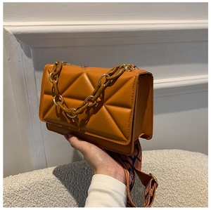 Detail of caramel quilted crossbody bag with chunky chain handle and patterned wide strap
