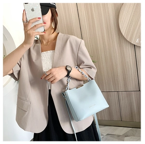 Detail of light blue crossbody bucket bag with resin chain handle and fashion text