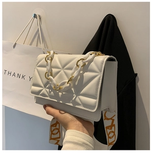 Close-up of white quilted crossbody bag featuring gold chain handle and wide strap