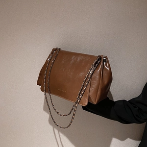 Détail du sac bandoulière en cuir brillant marron foncé avec chaîne et rabat
