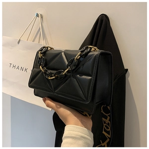 Close-up of black quilted shoulder bag with chic gold and acrylic chain handle detail