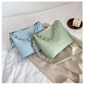 Close-up of light blue and green PU leather chain bags with gold and acrylic handles