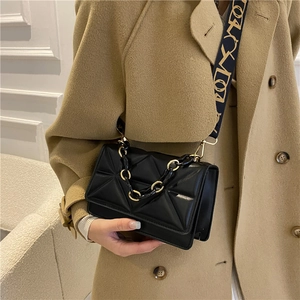 Quilted black crossbody bag with geometric patterns and dual chain straps on a stylish model