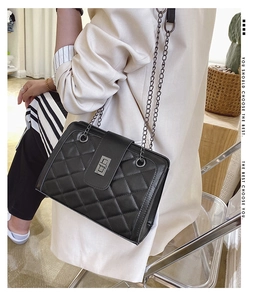 Detail shot of the quilted pattern and metal chain strap on this black shoulder bag