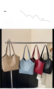 Four woven tote bags in khaki, light blue, burgundy and black hanging on a metal rack