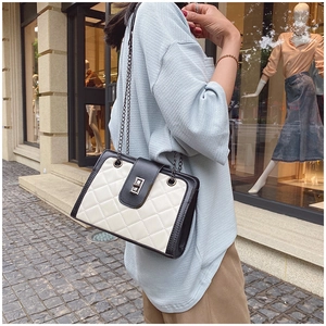 Detail of quilted diamond pattern and bicolor leather strap on a stylish chain bag
