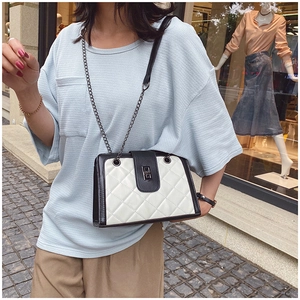 Detail of quilted leather crossbody bag featuring silver metal clasp and chain strap