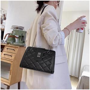 Close-up of a black quilted leather chain bag with a vintage metal twist lock closure