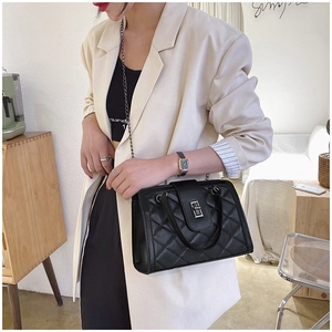 Close-up of black quilted shoulder bag with silver twist lock and metal chain strap