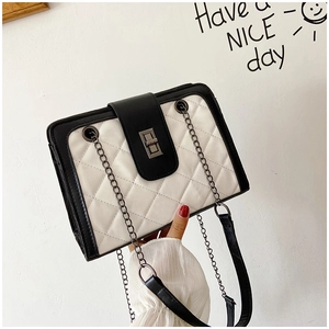 Detail of black and white quilted crossbody bag with metal twist lock and chain strap