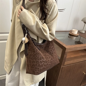 Close-up of leopard print hobo bag with wide leather strap and cute dog charm detail