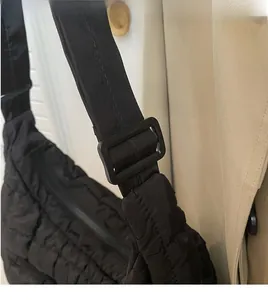 Detail of adjustable black shoulder strap and buckle on quilted nylon dumpling bag
