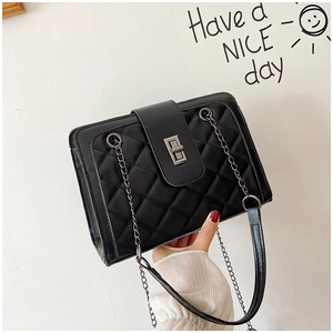 Close-up of black quilted shoulder bag with silver metal twist lock and chain strap