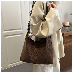 Detail of leopard print hobo bag with a decorative baseball bat keychain charm