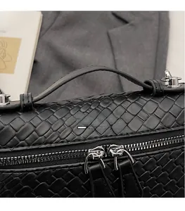 Detalle de textura trenzada negra y cremalleras plateadas en bolso elegante