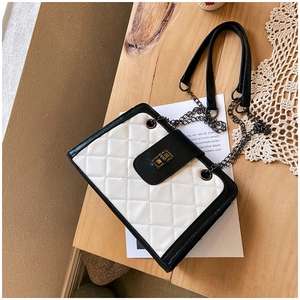 Top view of black and white quilted chain shoulder bag with metal lock on a wooden desk
