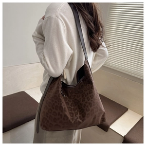 Detailed view of the leopard print tote bag with brown straps worn on the shoulder