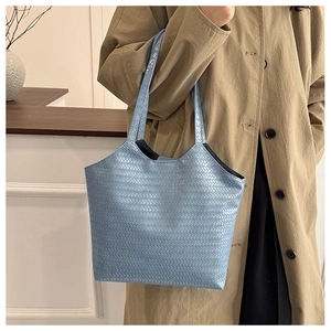 Detail of light blue woven tote bag with premium texture and flat shoulder strap handle