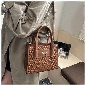 Close-up of brown PU leather tote bag featuring quilted texture and gold bow detail