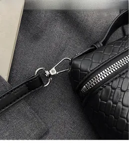 Vista detallada del gancho de metal plateado y la textura de cuero tejido de un bolso