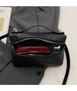 Detail view of black woven texture box bag showing interior capacity and metal zipper