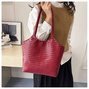 Detail of dark red woven tote bag featuring intricate V-shape texture and long handles