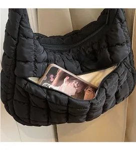 Close-up of front zipper pocket on black quilted tote bag showing storage for a phone