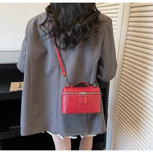 Detail of red woven texture mini crossbody box bag with silver hardware on a gray blazer