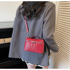 Red crocodile texture crossbody box bag worn with a grey blazer in a stylish interior