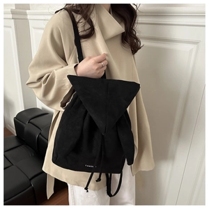 Detail shot of a black drawstring backpack with cute plush rabbit ears on the top flap