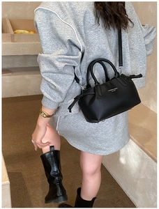 Detail of black lychee grain leather handbag with fashion logo and side drawstring texture