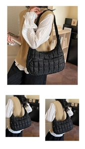 Detail of black quilted puffer shoulder bag featuring smooth zipper and nylon texture