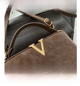 Close-up of vintage brown bag showing natural cracked texture and gold V-shaped hardware