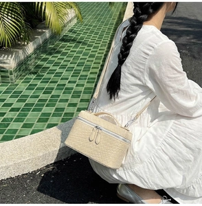 Outdoor shot of a beige woven box bag with silver hardware and a chain strap