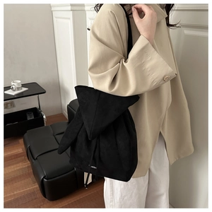 Detail view of the black suede backpack featuring unique rabbit ear-shaped fold design
