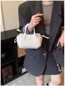 Close-up of white lychee pattern leather handbag with drawstring detail and metal logo