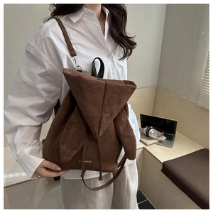 Detail view of brown suede backpack featuring cute rabbit ear lid and fashion lettering
